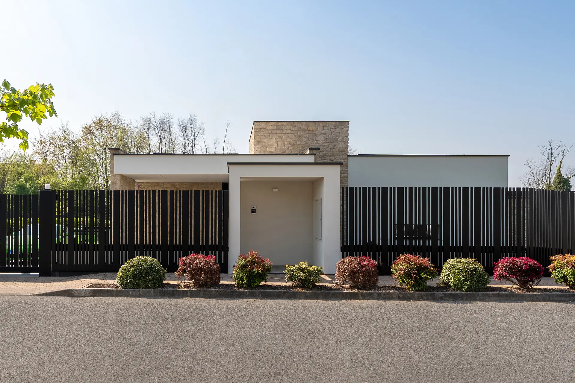 Villa Metafisica a Erbusco, ingresso principale con recinzione a lamelle verticali e rivestimento in pietra