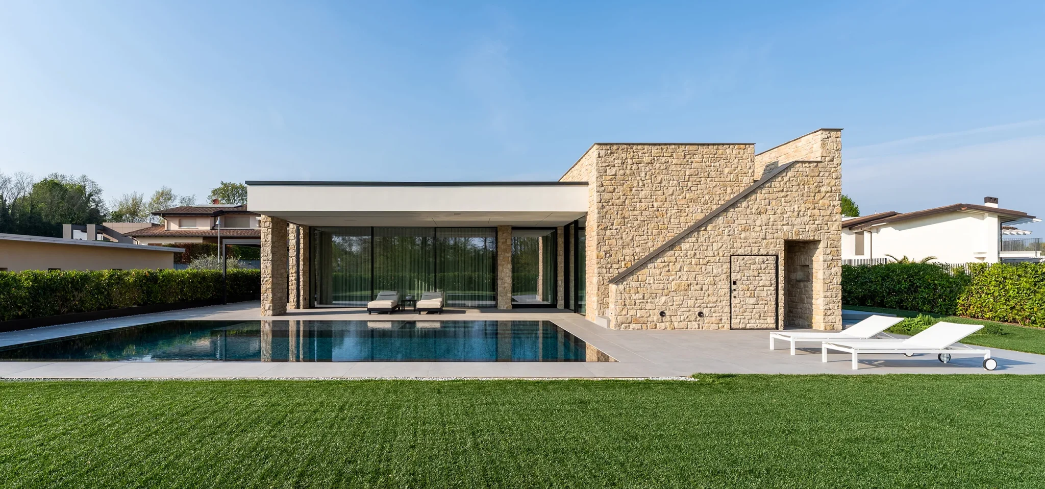 Villa Metafisica a Erbusco, vista esterna della villa contemporanea con piscina e rivestimento in pietra